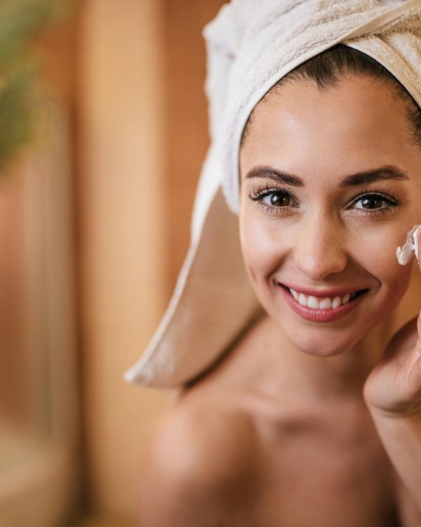 beautiful-woman-applying-moisturizer-her-face-bathroom